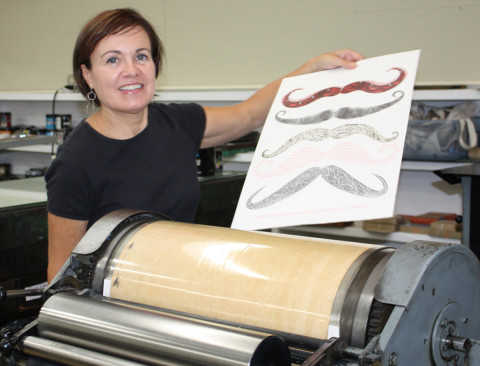 Laurie Corral, owner of BookWorks in West Asheville, pulls a print off one of the Vandercook presses. Photo courtesy of BookWorks
