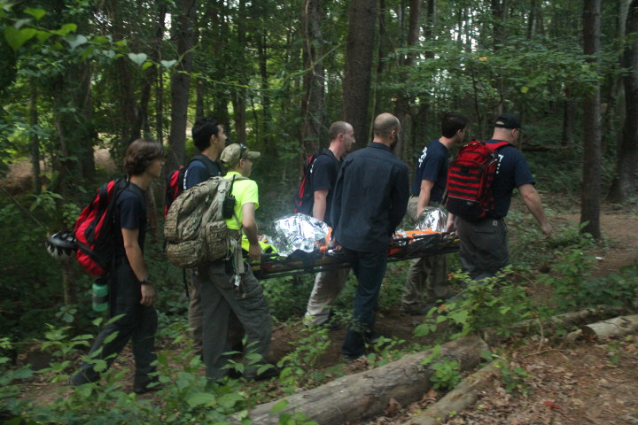 Squad volunteers carry a (simulated) wounded biker out of the woods. (Mountain Xpress / Jesse Farthing)