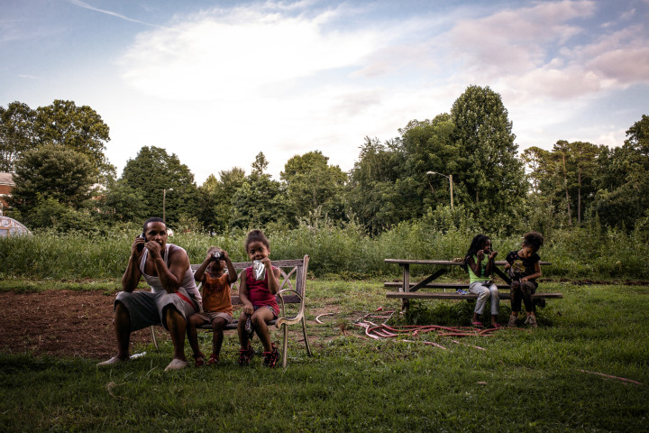 Sir Charles Gardner (left) sits with his daughter and her friends during a summer evening in the Pisgah View Community Peace Garden. 