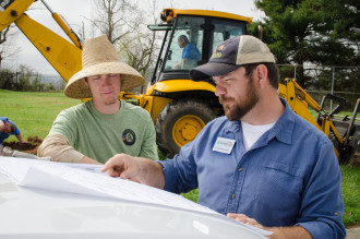 Asheville GreenWorks staff (from left) Forest Tapley and Eric Bradford examine the site plans for the Hillcrest community orchard. 