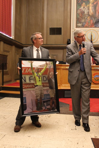 Councilmen Gordon Smith and Jan Davis present photo of a victorious City Manager Gary Jackson after a recent bicycle race.