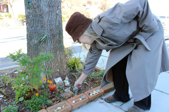 Carol Hubbard adds a stone she decorated to a garden tableau on Page Avenue. Photo by Virginia Daffron