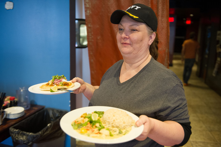 CHANGING TIMES: Server Deena Jackson brings food out at Blue Dream Curry House. Blue Dream recently converted to a no-tipping system, opting to pay servers and other employees a living wage rather than the industry standard of $2.13 per hour plus gratuity. 
