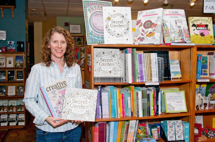 CRAYONTASTIC: Linda-Marie Barrett, general manager of Malaprop's Bookstore and Café, shows off some popular adult coloring books. Along with grown-up themes, the trend has also fostered coloring groups and meetups.