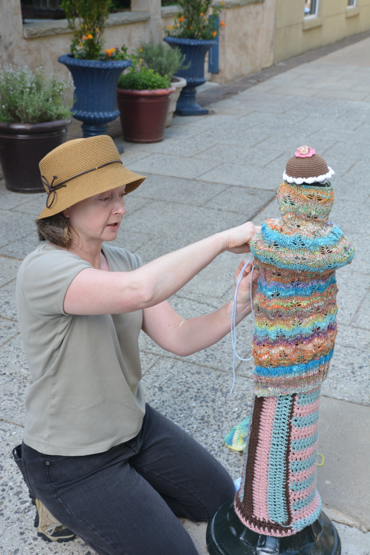 Kim Coyne finishes attaching a cozy to a post on Wall Street.