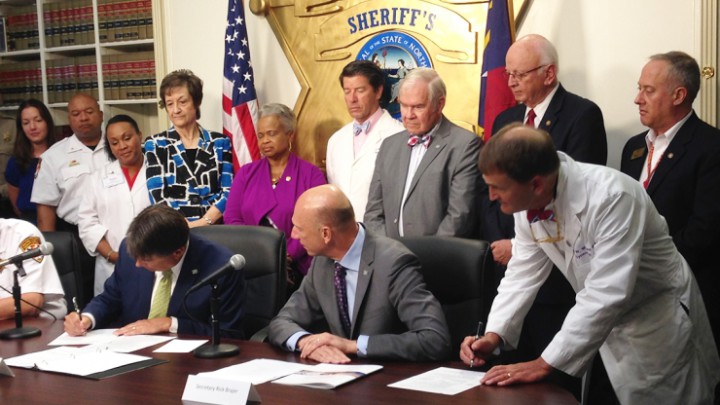 INTO ACTION: Gov. McCrory (left), along with DHHS Secretary Rick Brajer (center) and State Health Director Dr. Williams (right),  signs SB 734 into law June 20. Photo courtesy of NC DHHS