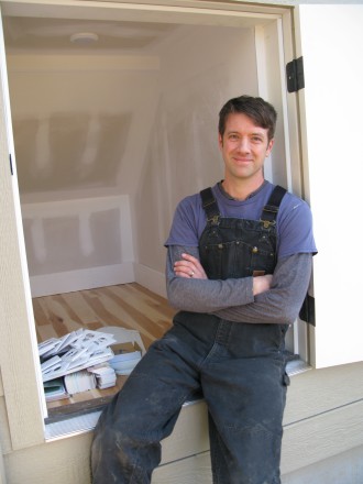 USING EVERY INCH: Teal Brown, owner of Wishbone Tiny Homes in Asheville, next to a storage space — accessed from the outside — within the tiny home he is building at 35 Fulton St. Photo by Mike Cronin
