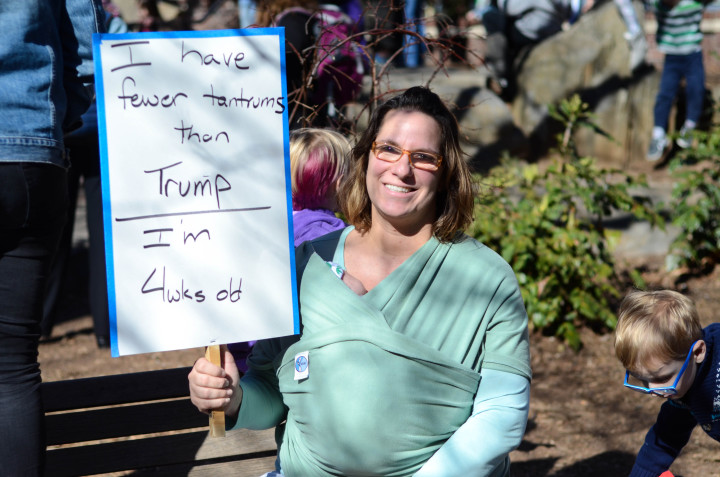 Angela, a protestor, holding her protest sign while cradling her four-week old baby.