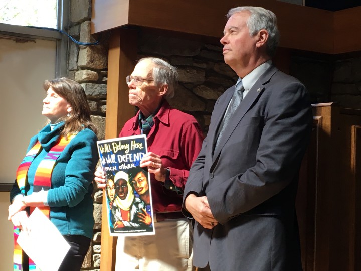 Jim Abbott, center, retired Episcopal priest, holds a poster supporting sanctuary for immigrants. 