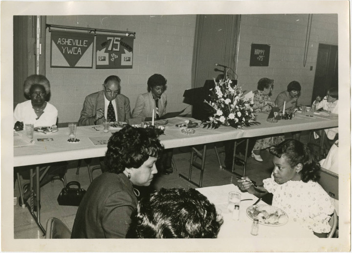 DINNER IS SERVED: Thelma Caldwell (back left), eats among members of the YWCA during its 75th anniversary celebration. Photo courtesy of UNC Asheville's Special Collections 