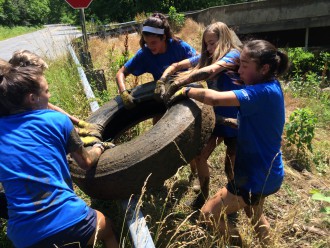 TRIALS & TRIBUTARIES: Maintaining the health of French Broad tributaries like the Ivy River is essential not only to the watershed's overall water quality, but for the rural communities that rely on these streams and creeks for drinking water and recreation purposes. Here, MAdison County students remove tires from the Ivy River. Photo by Mariah Hughes; courtesy of Ivy River Partners.