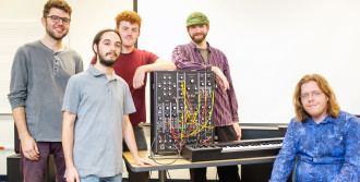 UNC Asheville graduates now working at Moog Music (from left) Kevin Carballo, Zac Fischman, Dylan Jordan, and (seated) Will Sparger, with Elijah Brown (in green hat), senior music technology student at the university. Photo courtesy of UNC Asheville
