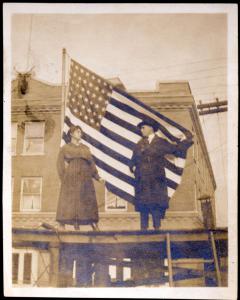 STARTS AND STRIPES: According to the N.C. Room, the image is of Mr. and Mrs. John A. Roebling, standing before the flag at the corner of Haywood and Walnut streets, circa 1917-1918. Photo courtesy of North Carolina Collection, Pack Memorial Public Library, Asheville