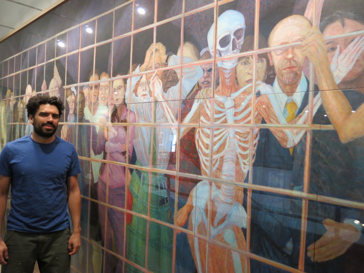 SELF-IMPRISONMENT: The Rev. Brian Combs, pictured, believes the fresco project at Haywood Street church will take roughly two years to complete. In the meantime, the nonprofit enjoys the series of egg tempera paintings donated by local artist Rob Rikoon, who is featured in the work to the right of the skeleton. Photo by Thomas Calder