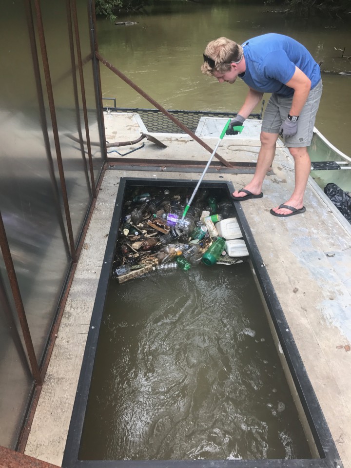 TRASHY WORK: An Asheville GreenWorks volunteer removes trash that’s been trapped in the mesh net of the Trash Trout. Volunteers kayak out to the contraption on a regular basis to clean it out. Photo by Eric Bradford/Asheville GreenWorks