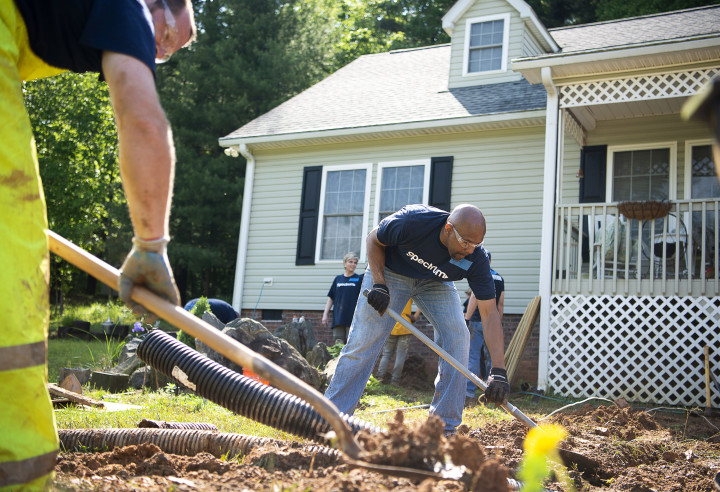 Spectrm volunteers dig holes for the ramp posts May 19 during the build day with Asheville Habitat Home Repair.