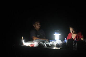 MIDNIGHT OIL: By the light of a lantern, a Vecinos staffer provides health services to a farmworker after the day's labor is done. Photo by Brian Elmore