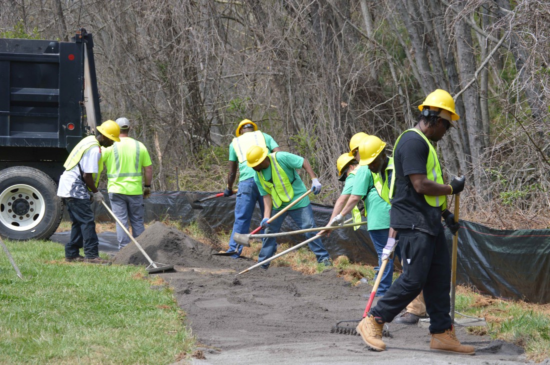 Students in the Green Opportunities Greenway Construction Training program smooth out the temporary trail on the Town Branch Greenway behind the Wesley Grant Southside Center.