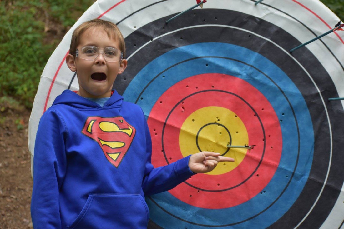 Young boy pointing to archery target