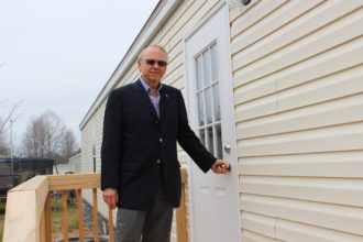 HOME SWEET HOME: George Morosani, the owner of Wellington Community Estates, stands at the entrance of a single-wide manufactured home. Morosani estimates that there are 2,000 people living in his park, which has more than 400 lots. Photo by David Floyd