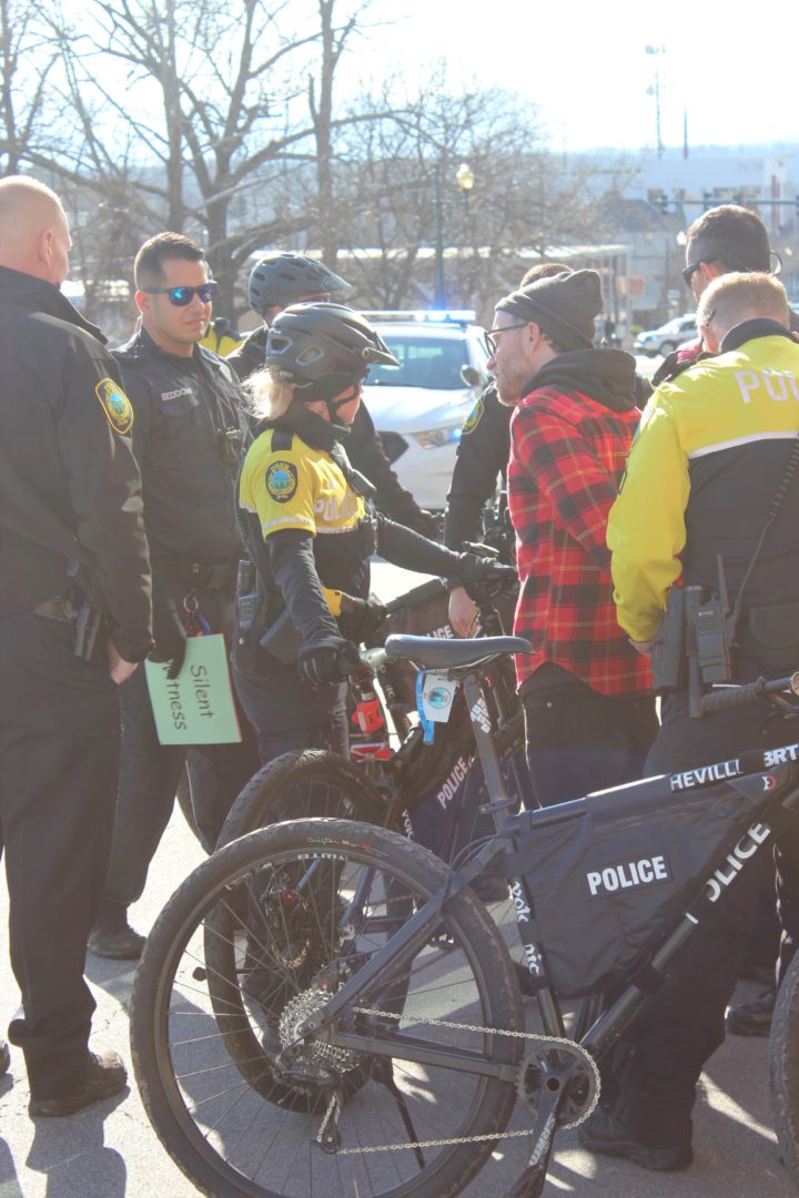 Bicycle police officer arrests an Extinction Rebellion WNC protester